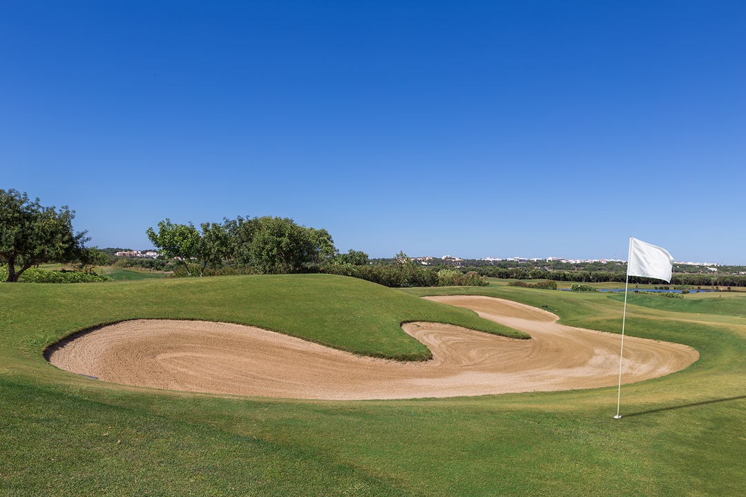 Sand trap on the golf course with a white flag.